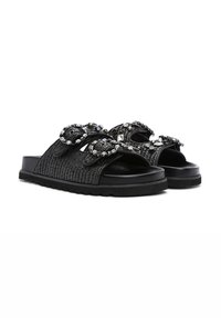 Zwarte schuifslippers met een gevlochten textuur, versierd met strassstenen en kraalaccenten op de banden. Platte rubberen zool voor comfort.