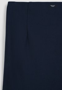 Tessuto blu navy con una superficie liscia, caratterizzato da un design piegato e un'etichetta piccola con la scritta "ZERO WASTE DESIGN" in alto.