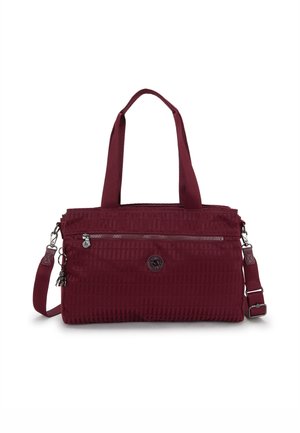 Burgundy tote bag with a textured surface, dual top handles, adjustable shoulder strap, and a front zip pocket. Features brand logo detail.