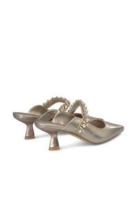 Talons hauts slingback métalliques dorés avec une pointe, ornés de strass transparents le long de la sangle, et un petit talon évasé.