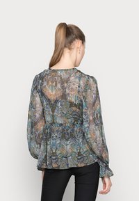 Blusa transparente e estampada com tons de azul, verde e castanho. Mangas longas e bufantes e detalhe de cintura franzida.