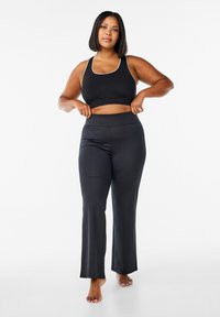 Zwart sportoutfit met een cropped tanktop met witte bies en hoge taille, flared broek, gemaakt van gladde, rekbare stof.
