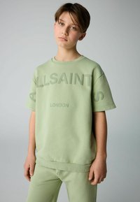 Lysegrøn sweatshirt med præget "ALLSAINTS LONDON" tekst, korte ærmer, rund hals og en afslappet pasform. Båret med matchende bukser.