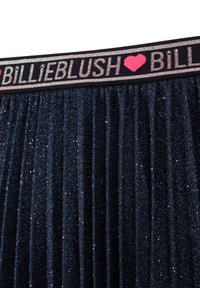 Námořnická skládací sukně s třpytivou texturou. Obsahuje elastický pas s textem "BILLIEBLUSH" v výrazných barvách a akcentem srdce.