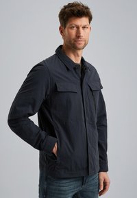 Dunkelblaue Jacke mit Reißverschluss vorne, zwei Brusttaschen und Seitentaschen. Hergestellt aus einem leichten, strukturierten Material mit einem klassischen Design.