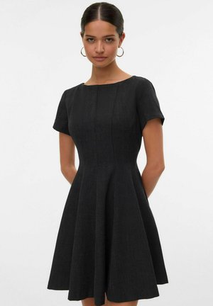 Zwart kortärmige jurk met een aansluitende bodice en een uitlopende rok. Gemaakt van gestructureerd materiaal met een ronde halslijn en verticale naaddetails.