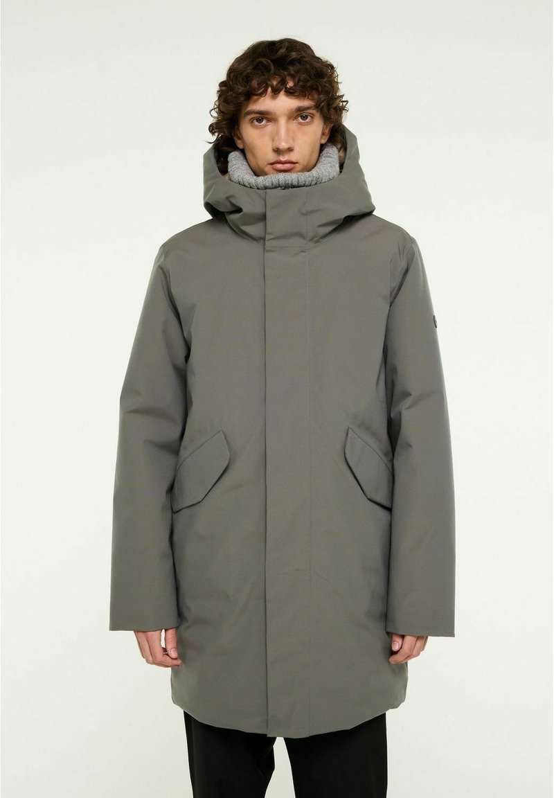 Grå vattentät parka med hög krage och stor huva, med sidfickor och rak silhuett. Slät textur, minimal design.