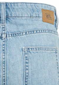 Lichtblauwe denim jeans hebben een leren patch met "camel active" branding, zichtbare stiksels en een standaard vijf-pocket ontwerp.