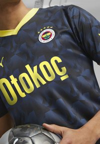 Tummansininen jalkapallopaita, jossa on geometrinen kuvio, keltainen "Otokoc" -teksti ja Fenerbahçe-joukkueen logo, jossa on viisi tähteä rinnassa.