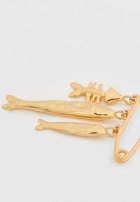 Παραμάνα σε σχήμα ψαριού χρυσού χρώματος που παρουσιάζει τρία δεμένα ψάρια με λαμπερό μεταλλικό φινίρισμα και λεπτομέρειες στις επιφάνειες.