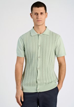 Kortärmad kabelstickad cardigan i pastellgrön, med krage och fem knappar, samt ribbad nederkant och ärmslut.