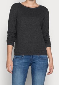 Tmavě šedá, texturovaná mikina s dlouhým rukávem, kulatým výstřihem a žebrovanými manžetami, kombinovaná s modrými džínami.