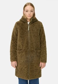 Bruine nepbontjas met capuchon, ritssluiting, twee voorkruiken en een zachte, gestructureerde afwerking. Ontworpen voor warmte en comfort.