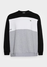 Sudadera con bloques de color que presenta secciones en negro, blanco y gris. Confeccionada en un tejido suave con puños de canalé y cuello redondo. Incluye un detalle de logo.