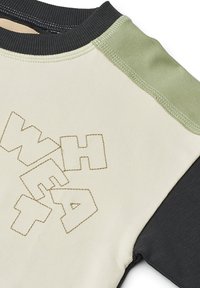 Maglia a collo rotondo in cotone con corpo beige, maniche nere, accenti verdi sulle spalle e testo in rilievo "WEAR" con cuciture a contrasto.