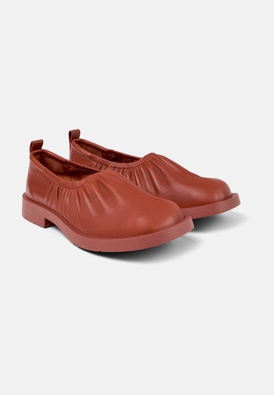 Red leather slip-on shoes with a rounded toe, elastic gathering at the top, and a durable rubber sole, featuring a flat design and no laces.