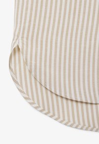 Gebogter Saum aus beige-weiß gestreiftem Stoff mit vertikalen Streifen und seitlichem Schlitzdetail, zeigt saubere Nähte und eine glatte Textur.