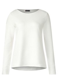 Haut à manches longues blanc avec un design texturé et un col rond, présentant un ourlet légèrement courbé et un tissu doux.