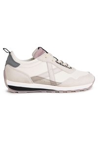 Zapatillas deportivas en beige claro con materiales de ante y malla. Presentan una tapa de talón gris, cordones, acentos transparentes y una suela negra con relieve.