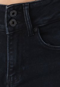 Dark blue denim jeans with a high waist, featuring black button hardware and subtle tonal stitching along the seams and pockets.