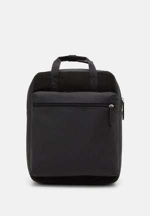 Sac à dos rectangulaire noir avec poche zippée à l'avant, double poignée en haut, tissu lisse contrastant avec un panneau arrière texturé.