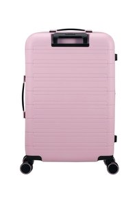 Valise rigide rose avec des rainures verticales, des accents noirs, une poignée supérieure et quatre roues multidirectionnelles pour une mobilité facilita.