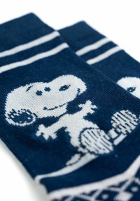 Calzini blu realizzati in tessuto lavorato a maglia presentano un design di Snoopy bianco con accenti rigati vicino ai polsini. La texture appare liscia e uniforme.