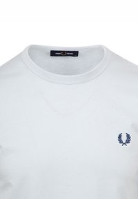 T-shirt bianco in cotone con colletto rotondo e un piccolo logo di alloro ricamato in blu navy sul petto. Tessuto morbido, vestibilità classica.
