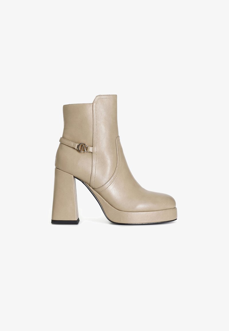Bottine en cuir beige avec un épais talon bloc, bout arrondi, détails de couture et accent métallique sur le côté. Texture lisse.