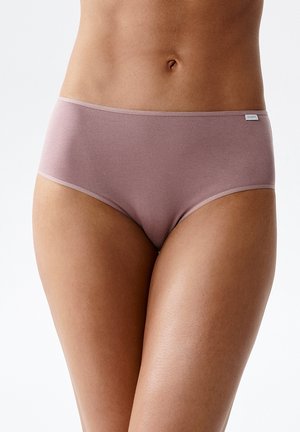 Kobieta w makowej, bezszwowej bawełnianej bieliźnie z wysokim stanem, pokazująca brzuch i górną część ud na jednolitym tle.