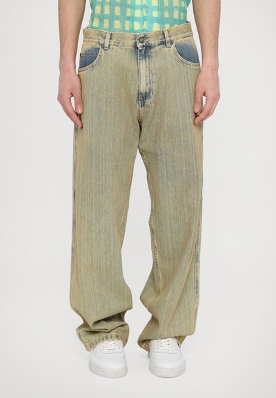 Light blue wide-leg jeans with a slightly faded finish, five pockets, and contrasting stitching, paired with white sneakers.