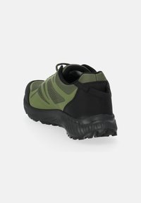 Scarpe da ginnastica verdi e nere con superficie texturizzata, collare imbottito e suola in gomma progettata per trazione e stabilità.