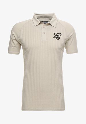 Polo beige con textura acanalada, mangas cortas tipo raglán, un placket de tres botones y un logo negro bordado en el pecho.