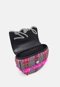 Mini borsa in tweed con accenti di pompon rosa, hardware in argento e un interno in pelle nera; presenta una forma curva e una chiusura a scatto.