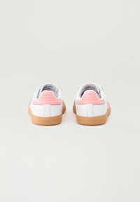 White sneakers with pink accents and a textured back. Rubber soles with a smooth finish. Simple design and low-top shape.