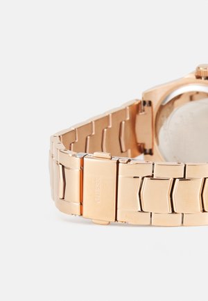 Rožinio aukso metalinis laikrodis su tekstūruota, tarpusavyje susijungiančia apyranke ir blizgiu užtrauktuku. Jame yra paprasta apvali korpusas ir lygus nugarėlė.