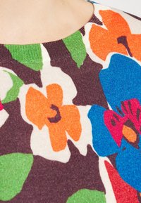 Sweter w kwiatowy wzór z pomarańczowymi, niebieskimi i zielonymi kwiatami na brązowym teksturowanym tle oraz okrągłym dekoltem.