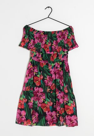 Blommig off-shoulder klänning med livfulla rosa och röda hibiskusmönster på en svart bakgrund, med smockad överdel och lagerkjol.