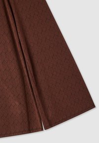 Tessuto marrone con un motivo geometrico di foglie in nero. Il materiale ha una texture liscia con una leggera lucentezza e dettagli di cucitura visibili.