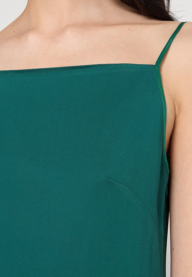 Grünes ärmelloses Oberteil mit quadratischem Ausschnitt, aus leichtem Stoff gefertigt, mit glatter Textur und dezenten Seitennähten.