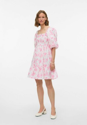 Bloemige jurk met roze tinten op een witte achtergrond, met gebloemde mouwen en een gerimpelde lijfje, eindigend in een gelaagde rok.