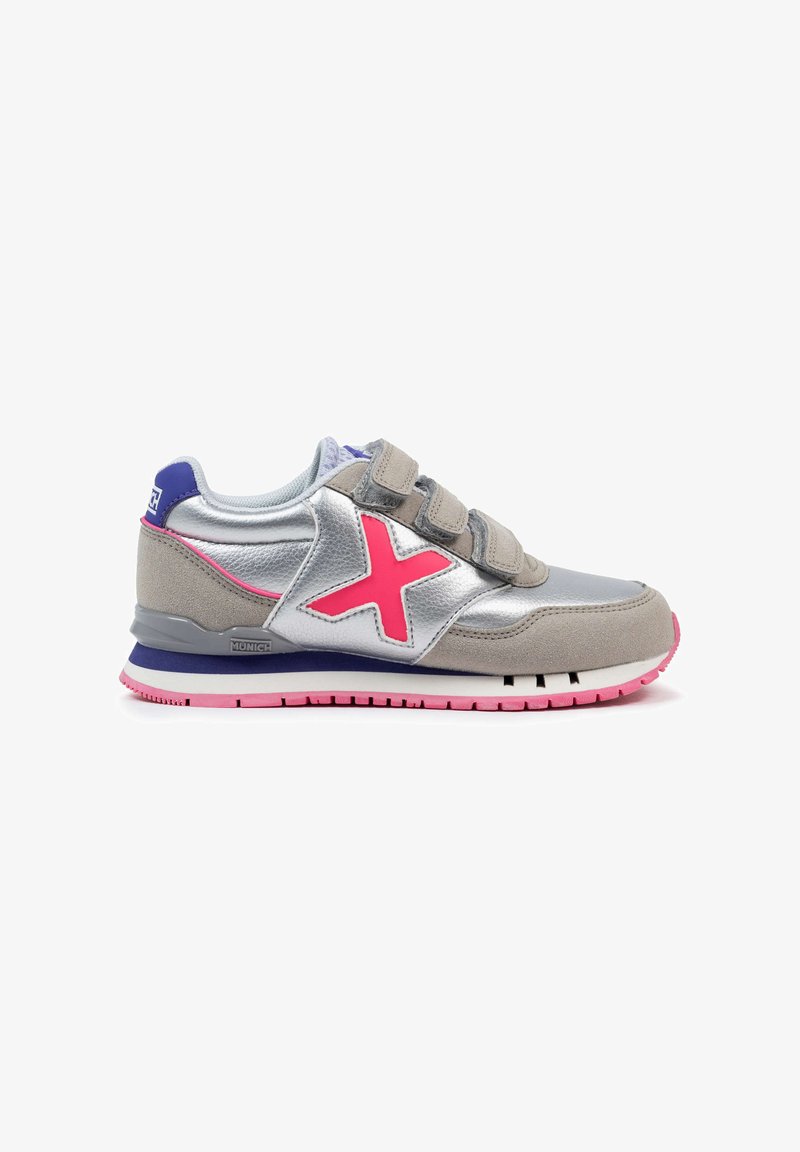 Zapatilla plateada y gris con acentos rosas, hecha de materiales de gamuza y sintético, con tiras de velcro y una suela texturizada, presentando un logo en el talón.