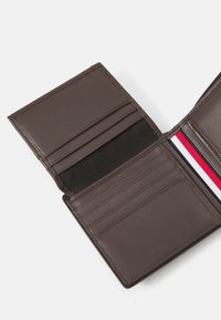 Brown leather wallet with multiple card slots, a textured interior, and a red, white, and blue stripe accent. Open and flat, showcasing design.
