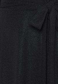 Lähikuva kiiltävästä mustasta kankaasta, jossa on teksturoitu pinta ja oikealla puolella sidottu nauha.