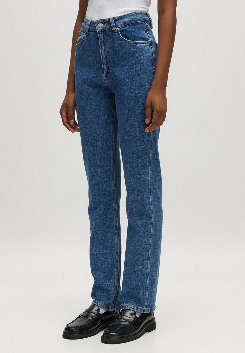 Jeans de tiro alto azules hechos de mezclilla, con un corte de pierna recta, diseño de cinco bolsillos y un cierre clásico de botón y cremallera.
