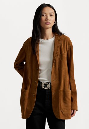 Brown suede blazer with a relaxed fit, featuring front buttons, a chest pocket, and two large front pockets. Paired with a white t-shirt.