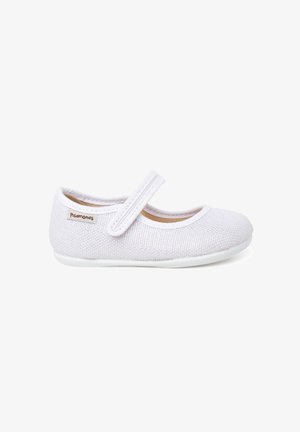 Chaussure Mary Jane blanche texturée avec une bride en Velcro et une petite étiquette de marque sur le côté, conçue pour les enfants.