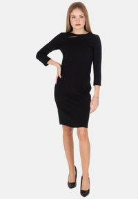 Abito nero fino al ginocchio con maniche a tre quarti e dettaglio a cut-out sul davanti. Realizzato in tessuto liscio con una silhouette aderente.