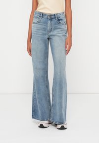 Lyseblå vide jeans laget av denim, med fem lommer, knappelukking og lett falming for ekstra tekstur.