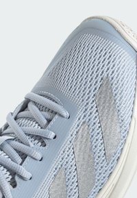 Ljusblå idrottssko med en texturerad mesh-överkonstruktion, syntetiska detaljer och vit sula. Har reflekterande silverränder och en rundad tå.